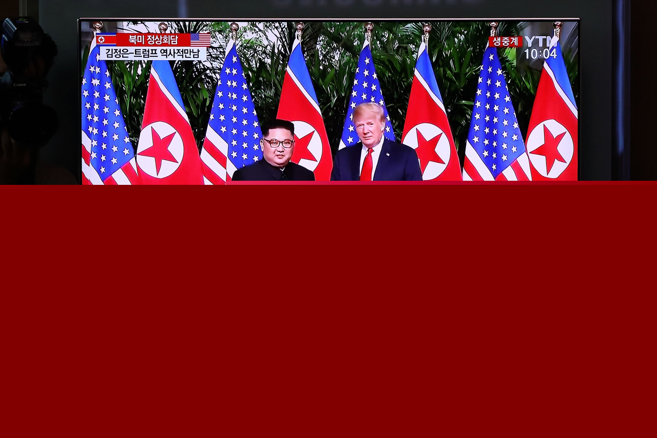People watch on a screen reporting on the former US President Trump meeting with North Korean leader Kim Jong-un at the Seoul Railway Station on Jun. 12, 2018 in Seoul. (Getty Images)