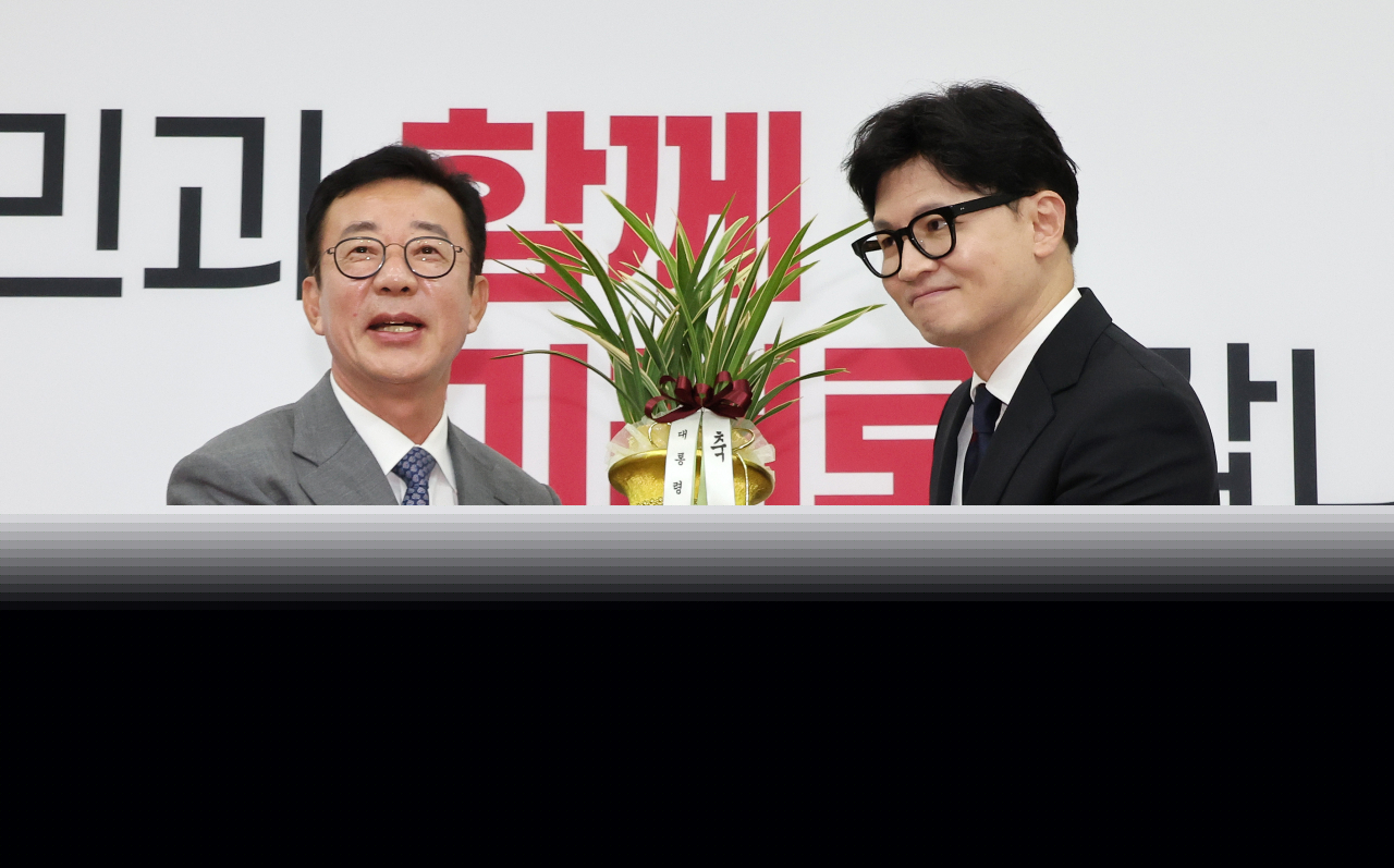 People Power Party Chair Han Dong-hoon (right) holds a Korean orchid gifted by Hong Chul-ho (left), senior presidential secretary for political affairs, as Han greeted Hong in the National Assembly in Seoul Wednesday. (Yonhap)