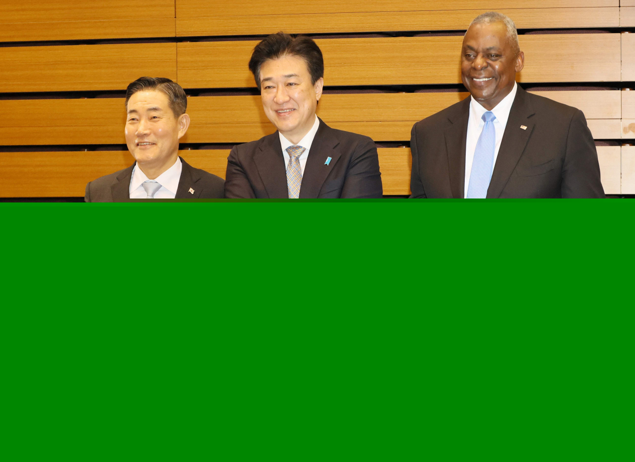 South Korean Defense Minister Shin Won-sik (left), US Secretary of Defense Lloyd Austin (right) and Japanese Defense Minister Minoru Kihara and shake hands as they exchange signed documents of their agreement of their partnership after a Japan-US-South Korea trilateral defense ministers meeting at Japan's defense ministry in Tokyo on Sunday.(Pool via AFP)