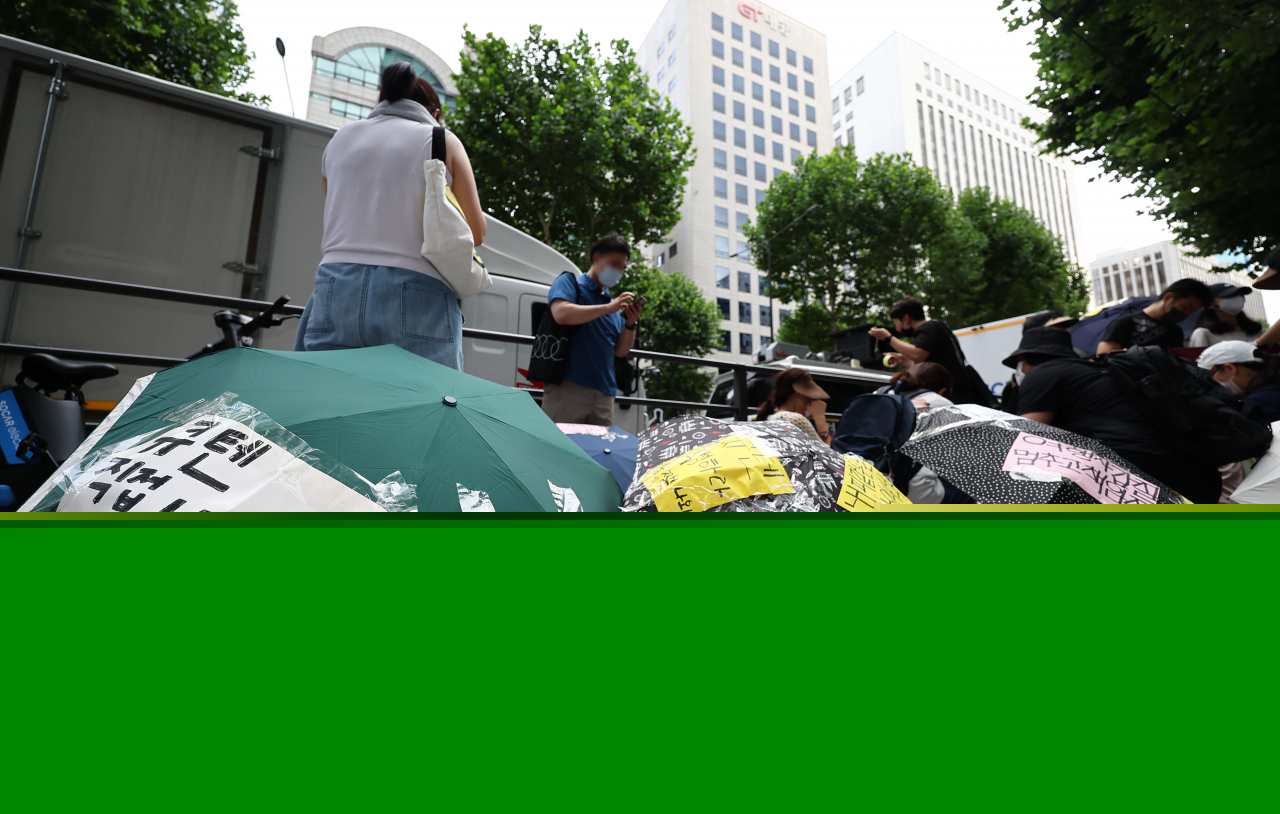 Consumers suffering from delayed payments from e-commerce platforms Tmon and WeMakePrice stage an umbrella protest, calling for apology and measures to recover damage, in front of the two platforms' owner Qoo10 headquarters in Seoul on Sunday. (Yonhap)